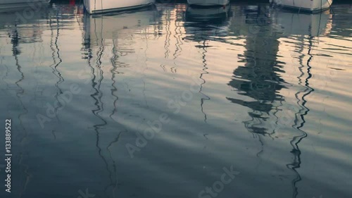 Sea idyll. The texture of the surface of the calm sea at sunset. Yachts in the sea port. Yacht reflection in water. Beautiful sunset on the background of the sea