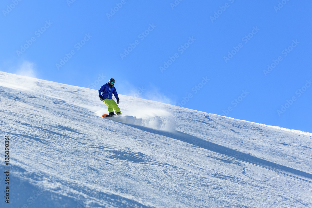Male snowboarder on the slope sliding down the slope