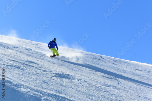 Male snowboarder on the slope sliding down the slope