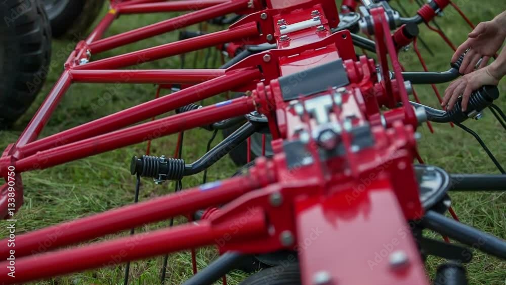 A young man is standing by the machinery and he is manually rotating rakes into one direction.
A young man is standing by the machinery and he is manually rotating rakes into one direction.
