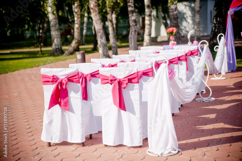 Close-up of white wedding chairs with purple ribbon © frizza
