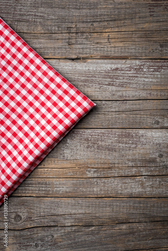 Red checkered tablecloth on wooden table with copyspace.