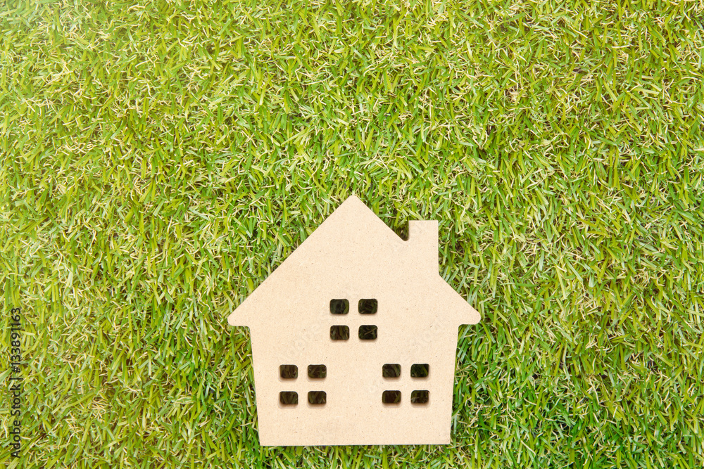 Wooden house toy on ground green grass with copy space.Real esta Wooden house toy on ground green grass with copy space.Real esta
