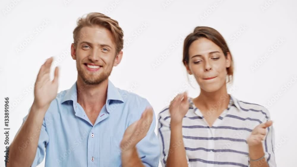 Young Caucasian couple smiling standing on white background and dancing the same with their hands Young Caucasian couple smiling standing on white background and dancing the same with their hands