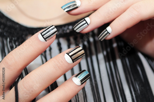 Gray striped nail design on female hand close up.