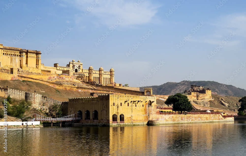 View of part of the ancient Amber fort, walls, gates and adjoining building with bridge from the Maota Lake. Jaipur, India.