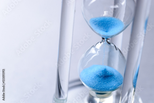 Close-up studio shot of hourglass with blue sand