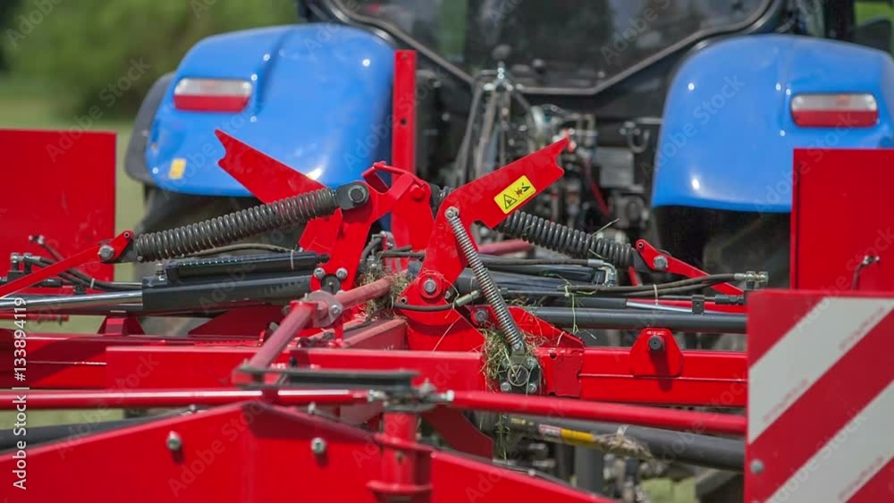 A young farmer on a blue tractor is pushing a button and he is slowly closing agricultural machinery for preparing hay.
A young farmer on a blue tractor is pushing a button and he is slowly closing agricultural machinery for preparing hay.