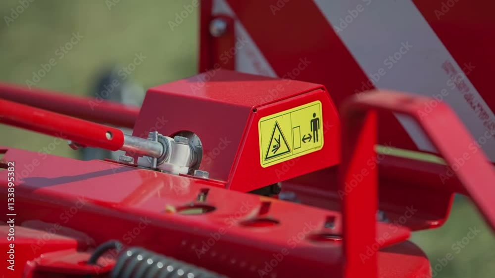 A young farmer is wearing protection gloves and he is winding a handle which belongs to a rotary hay rake.
A young farmer is wearing protection gloves and he is winding a handle which belongs to a rotary hay rake.