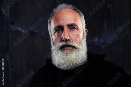 Close-up portrait of concentrated mature man with gray beard and © ArtFamily
