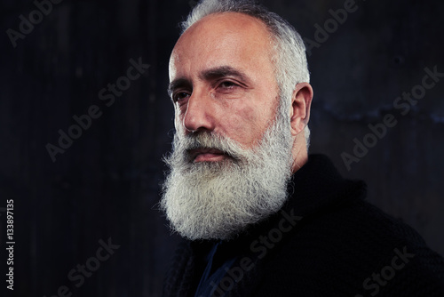 Portrait of stylish handsome male with beard posing in the darkn photo