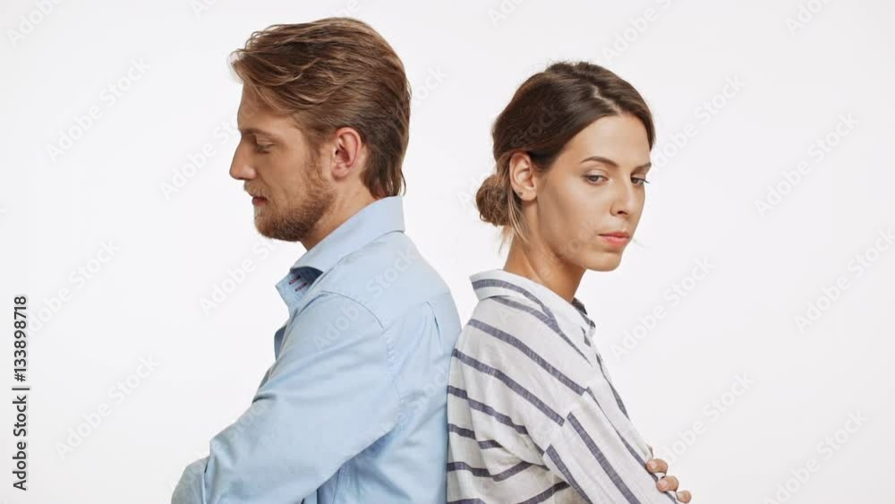 Young Caucasian pair standing back to back upset and in quarrel on white background in slowmotion Young Caucasian pair standing back to back upset and in quarrel on white background in slowmotion