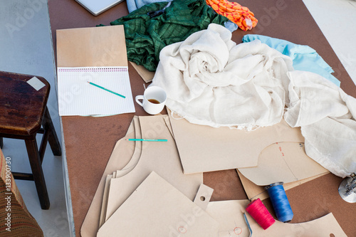 Overhead view of sketchpad and textiles on fashion design workshop table photo