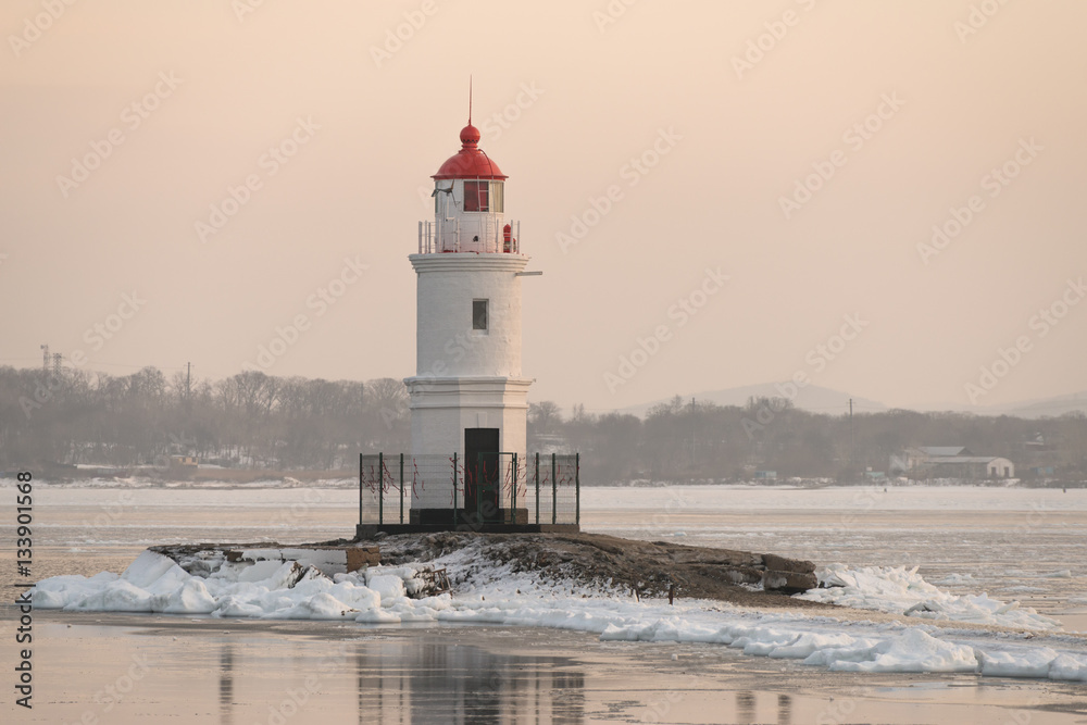 Lighthouse at sunset. Winter season.
