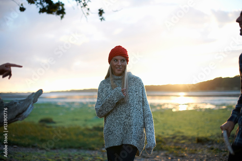 Young woman and male friends collecting sea driftwood at sunset photo