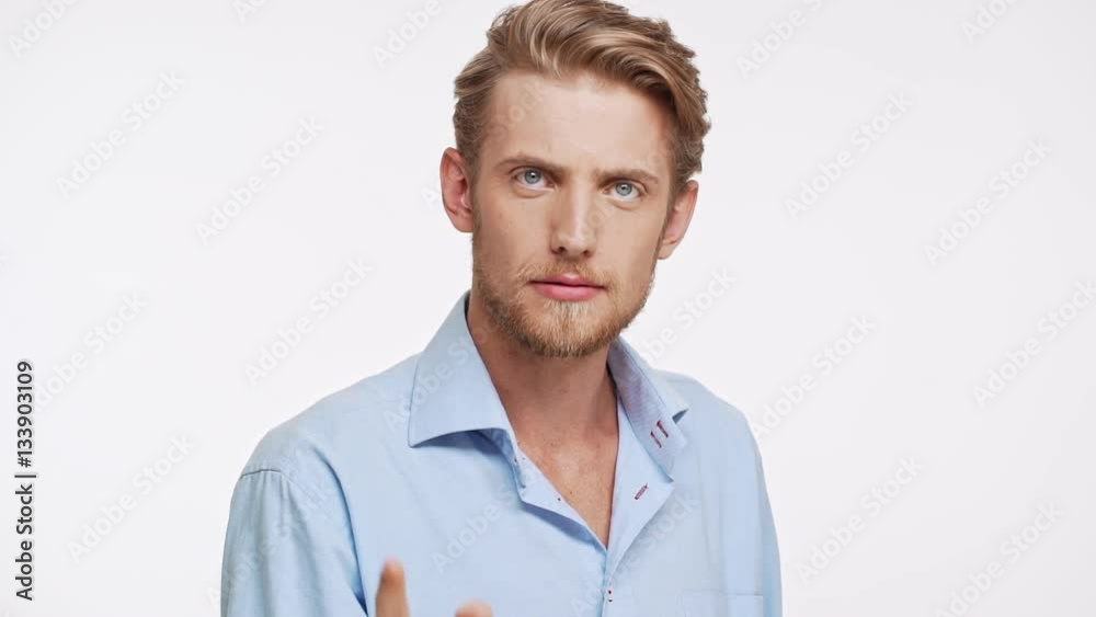 Young Caucasian male with brown beard and blue eyes standing on white background and jokingly blame shaking his hand in slowmotion Young Caucasian male with brown beard and blue eyes standing on white background and jokingly blame shaking his hand in slowmotion