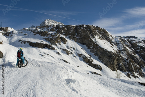 Sciatore con ebike - mountain bike elettrica - fat bike da neve, che sale in alta montagna con gli sci caricati sulla bici, Riale, Val Formazza, Ossola, Alpi Italia