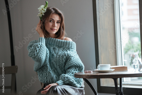 Pretty lady with flower on hairstyle sitting in cafe