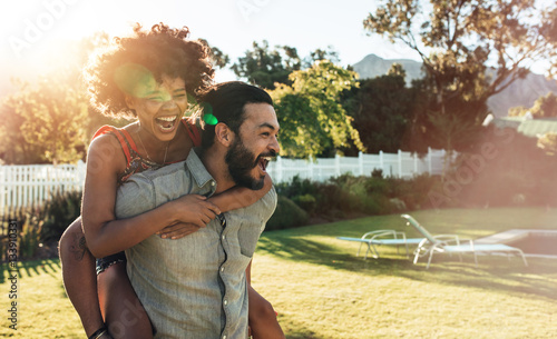 Young couple piggybacking in backyard photo