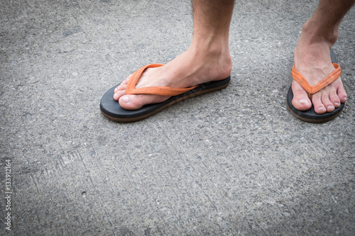 Feet of a man wearing sandals on the old concrete floor.