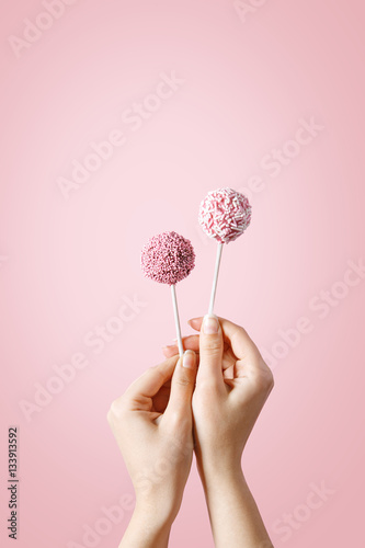 Woman hands holding pop cakes on pastel background photo