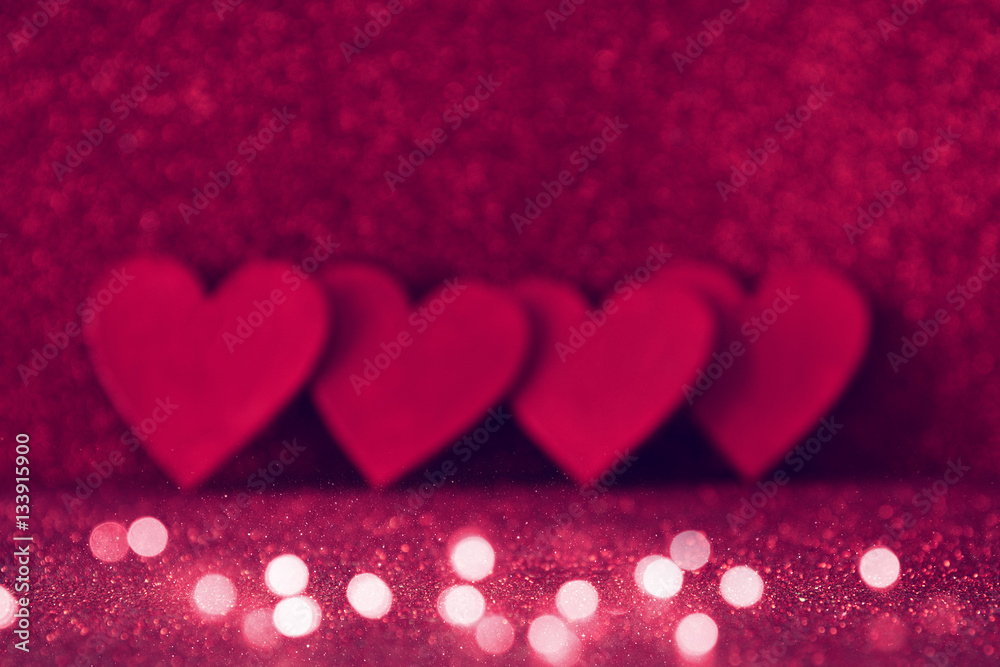 Wooden red hearts on red shiny background
