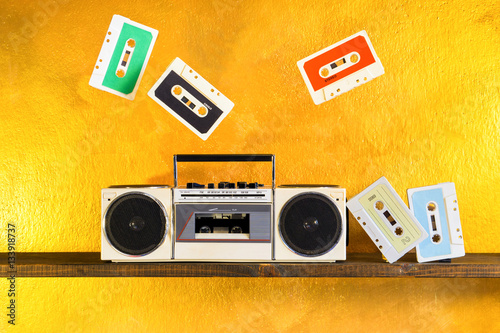 Radio tape recorder and music cassette player  on golden background - Boom box portable sound system retro style  - Concept of vintage and outdated entertainment technology  device