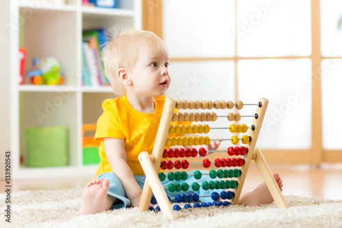 Preschooler baby learns to count. Cute child playing with abacus toy. Little boy having fun indoors at kindergarten, playschool, home or daycare centre. Educational concept for preschool kids.