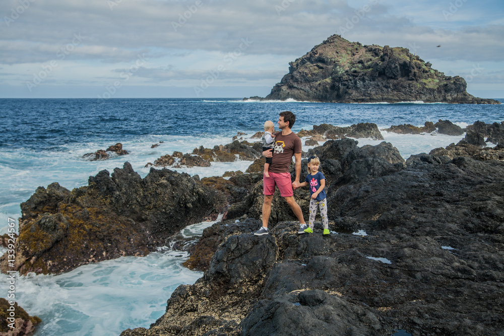 Father and children stay near the sea shore in Garachico, at the north of Tenerife, Spain