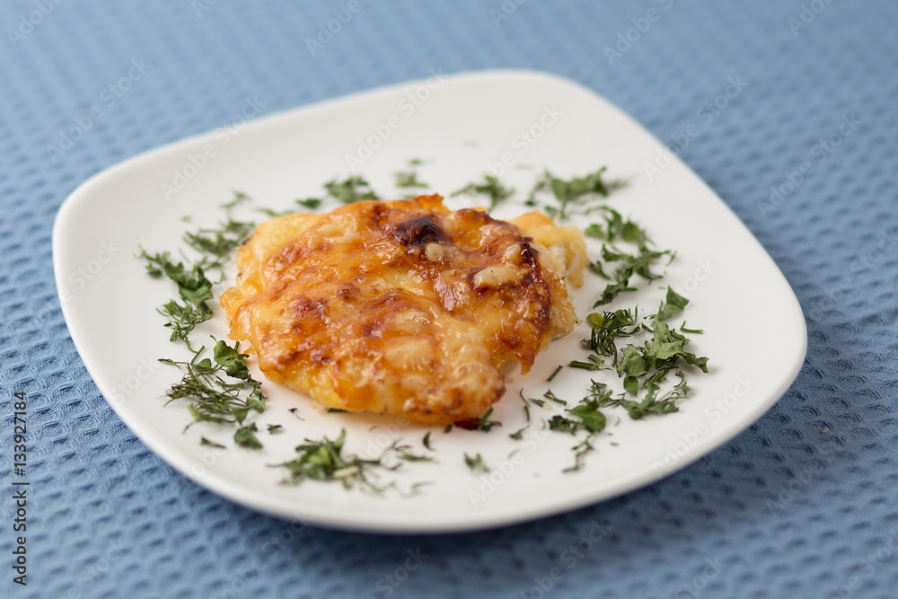 Chicken fillet under pineapple on a plate on a blue napkin