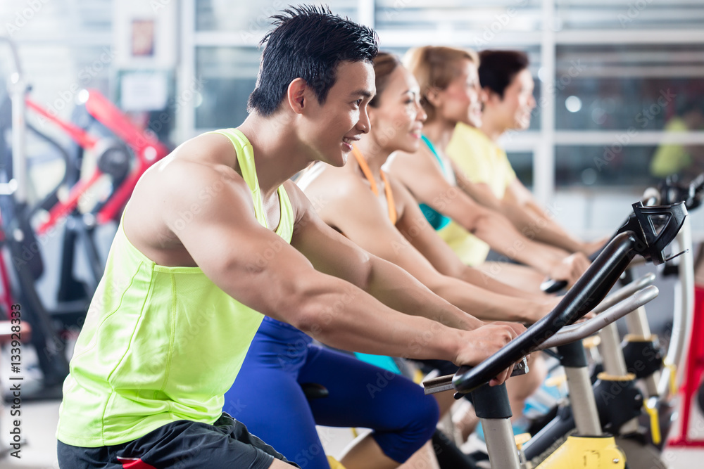 Young Asian athletes side by side in spinning class Young Asian athletes side by side in spinning class
