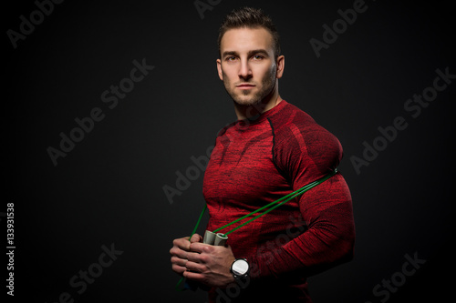 Muscular man skipping rope. Portrait of muscular young man exercising with jumping rope on black background.