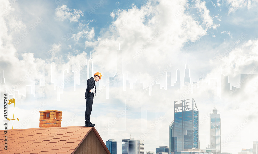 Engineer man standing on roof and looking down. Mixed media Engineer man standing on roof and looking down. Mixed media