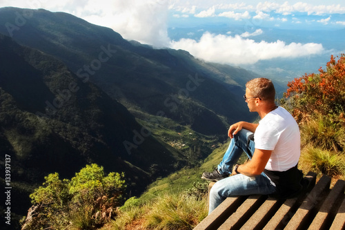 Man relaxes on the edge of the cliff . Plateau " End of the World " , Sri Lanka . © delbars