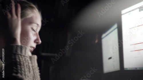 Nice girl sitting behind two monitors close-up