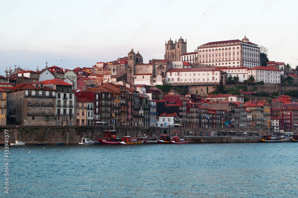 Naklejka premium Portogallo, 26/03/2012: barche al tramonto e lo skyline di Porto con vista del fiume Douro tra le città di Porto e Vila Nova de Gaia
