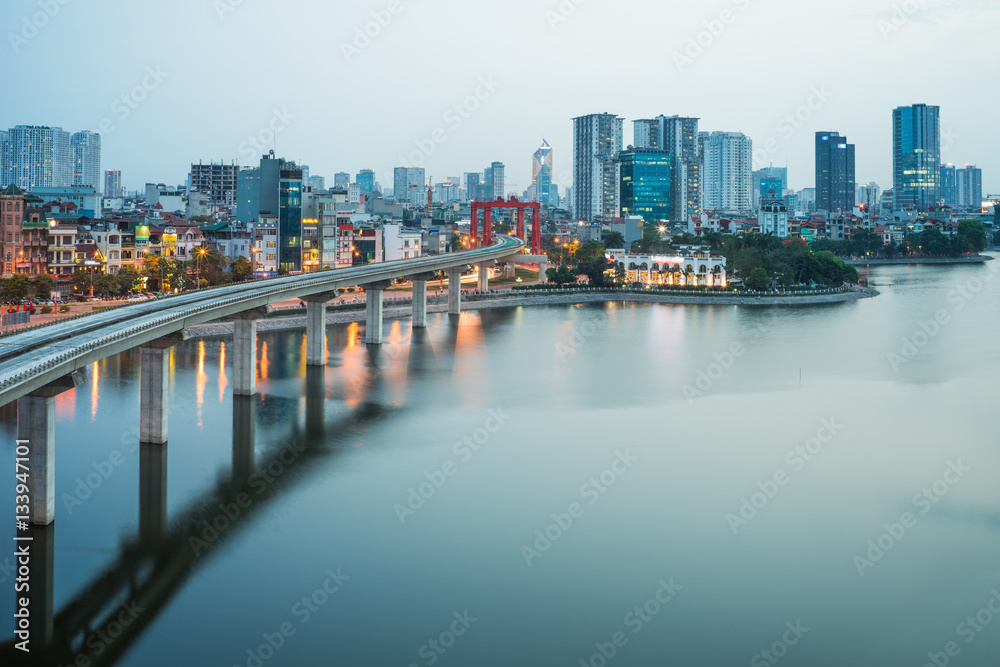 Naklejka premium Aerial view of Hanoi cityscape by twilight period, with Dong Da lake and under construction Cat Linh - Ha Dong elevated railway
