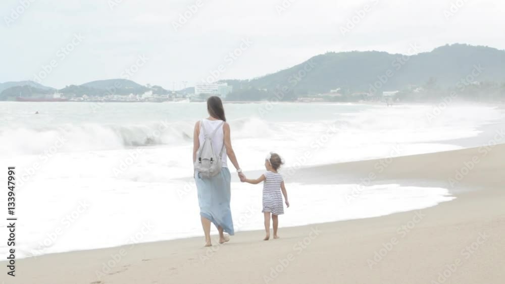 Mother with little daughter walking along the sea in bad weather Mother with little daughter walking along the sea in bad weather