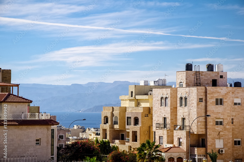 Aqaba city. Typical Aqaba buildings on the foreground. the Gulf of Aqaba and mountains on the background.