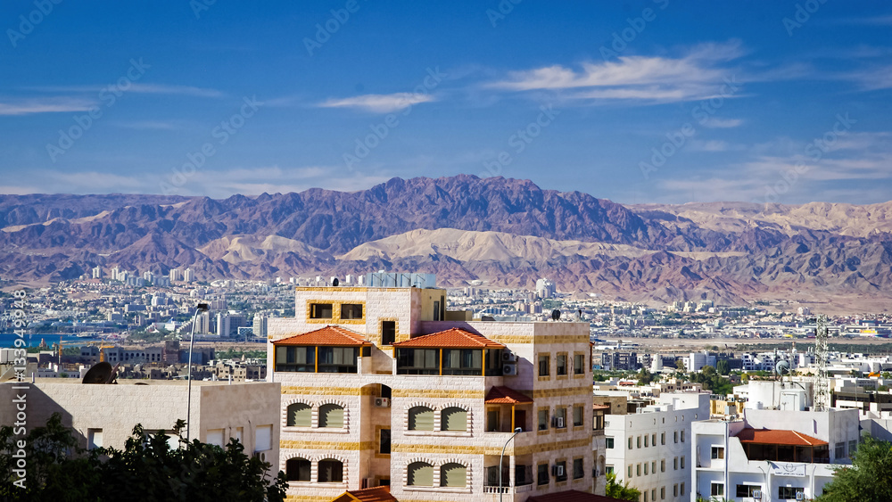 Aqaba city panorama. Some typical buildings on the foreground. City and the mountains on the background.