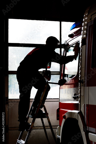 Firefighter cleans firetruck. Maintenance of fire equipment. Life at the fire station.