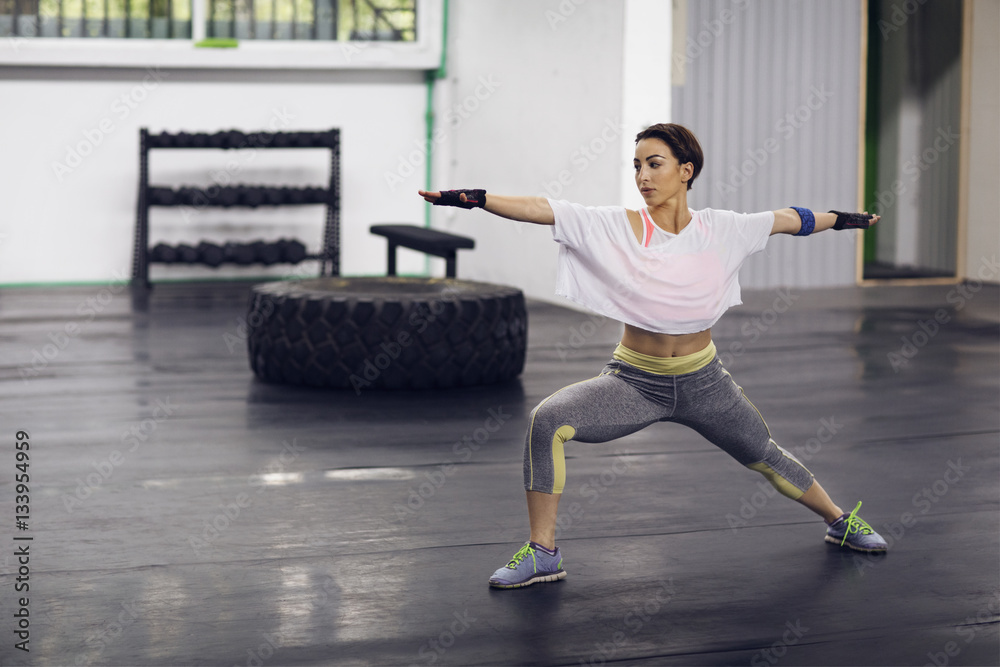 Determined female athlete exercising in Warrior 2 pose at gym Determined female athlete exercising in Warrior 2 pose at gym