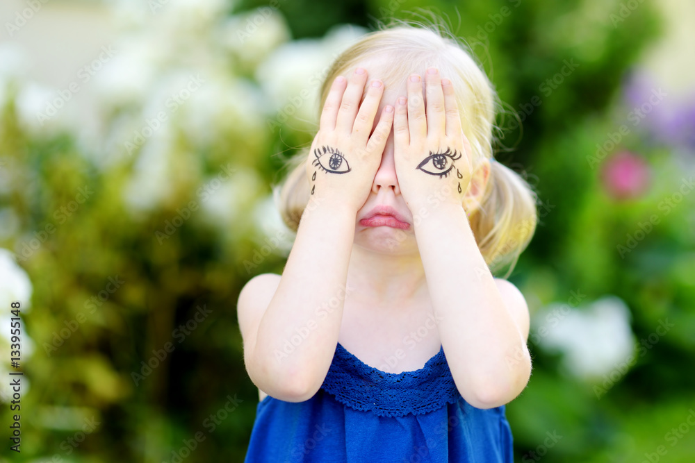 Cute little girl covering her face with her hands on summer day Cute little girl covering her face with her hands on summer day