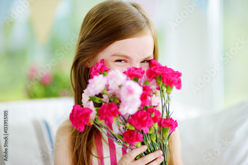 Adorable smiling little girl holding flowers for her mom