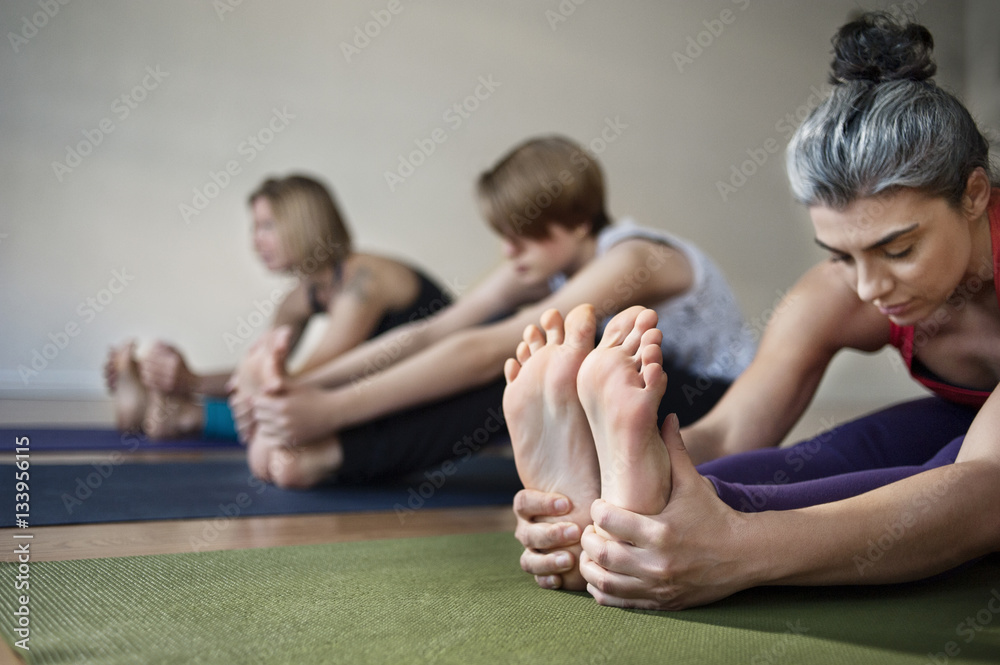 Female touching feet while doing yoga in health club Stock Photo
