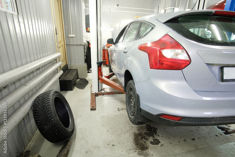 car on a lift in a car repair station car on a lift in a car repair station