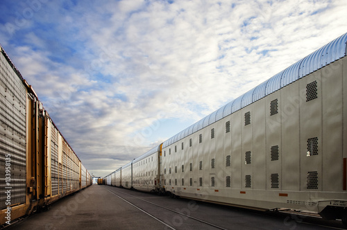 Trains at industry against cloudy sky photo