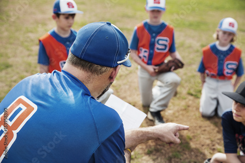 Coach pointing while discussing with baseball team on field photo