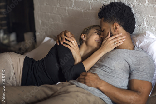 Young couple romancing on bed at home photo