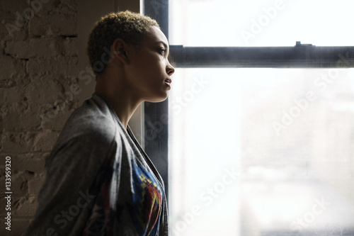 Side view of thoughtful woman standing by window at home photo